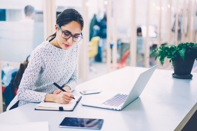 woman in eyewear planning writing in notebook